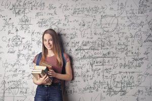 Dziewczyna trzymająca książki przed ścianą z wypisanymi formułami w Eldorado Oława.